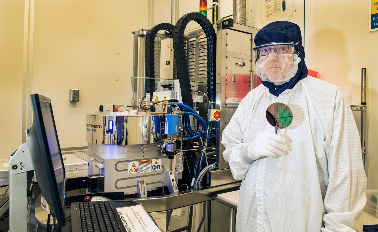 NIST process engineer Richard Kasica holding a silicon wafer beside real fabrication equipment